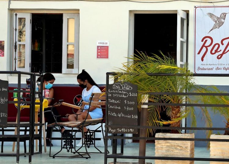 Dos mujeres esperan fuera del Bar Rojo, el 25 de agosto de 2021, en La Habana, Cuba. | Ernesto Mastrascusa, EFE.
