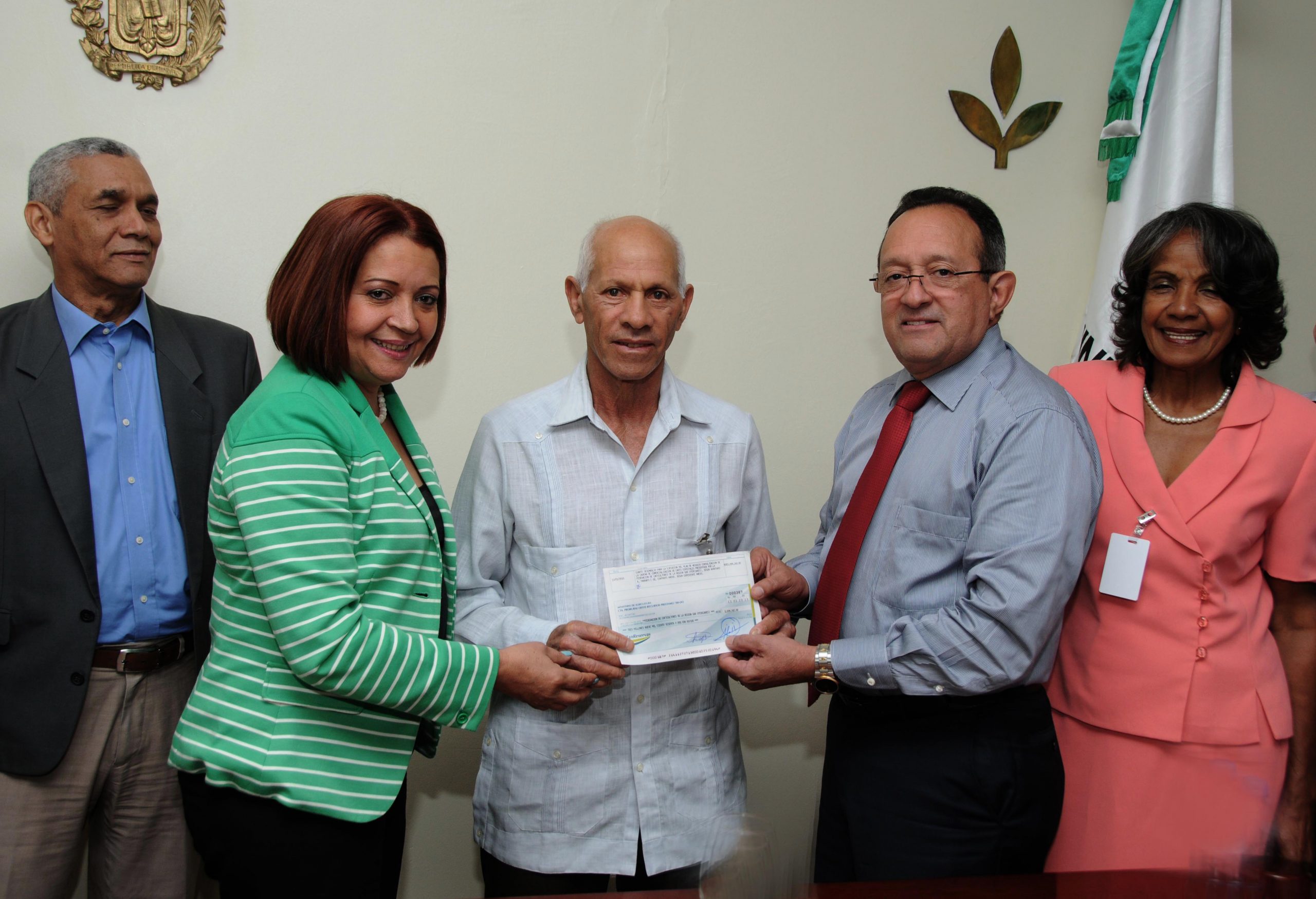 El ministro de Agricultura, Ángel Estévez y la directora de la Oficina de Ejecución de Proyectos, Argentina Betances,  entregan un cheque al productor Juan Franco Pujols, de la Federación de Caficultores de la Región Sur./elDinero