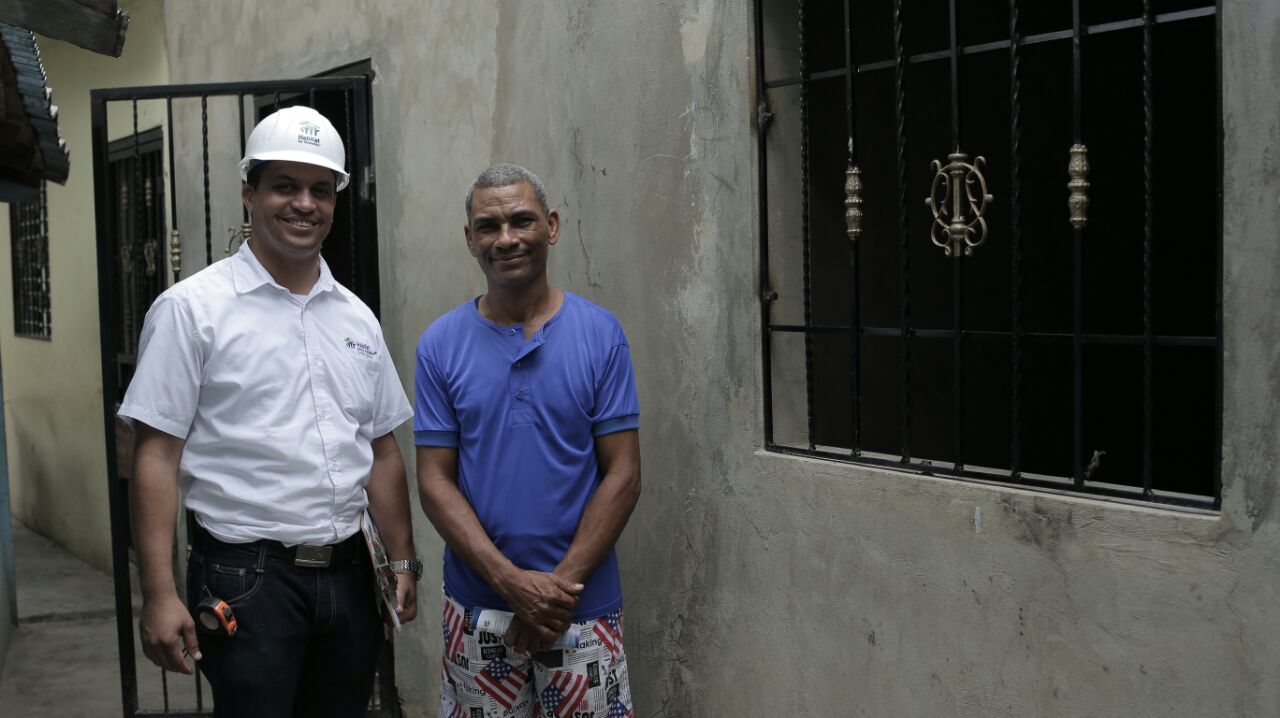 foto 1. un ingeniero de hábitat junto a un beneficiado y su mejora habitacional