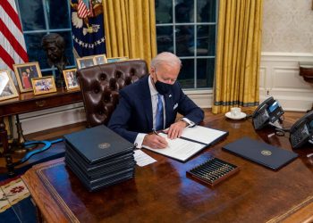 El presidente de EEUU, Joe Biden, firma un documento desde el Despacho Oval de la Casa Blanca.