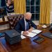 El presidente de EEUU, Joe Biden, firma un documento desde el Despacho Oval de la Casa Blanca.