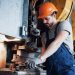 Portrait of a young worker in a hard hat at a large metalworking plant. The engineer serves the machines and manufactures parts for gas equipment