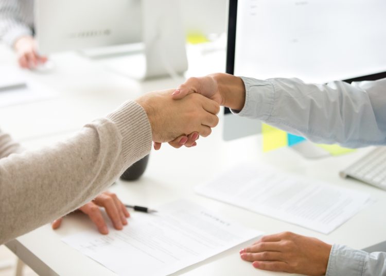 Handshake of man and woman after signing business contract, clos