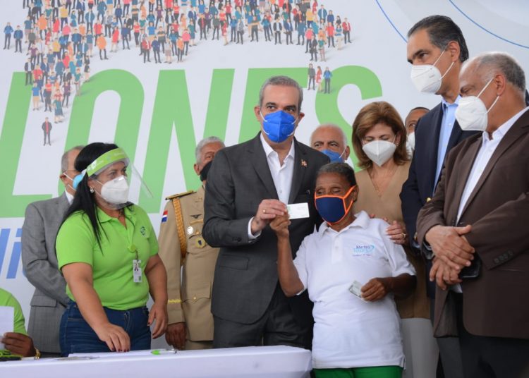 Luis Abinader, presidente de la República;  Raquel Peña, vicepresidenta de la República, y el Dr. Santiago Hazim, director ejecutivo de SeNaSa, durante la entrega del carnet como afiliada al Régimen Subsidiado de SeNaSa  a Estebania Soto.