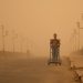 Un hombre empuja una carretilla durante una tormenta de arena. - Fuente externa.