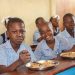 Niños haitianos reciben alimentos en un centro escolar apoyado por Mary's Meals, mientras la organización lanza un llamamiento urgente ante la crisis alimentaria.