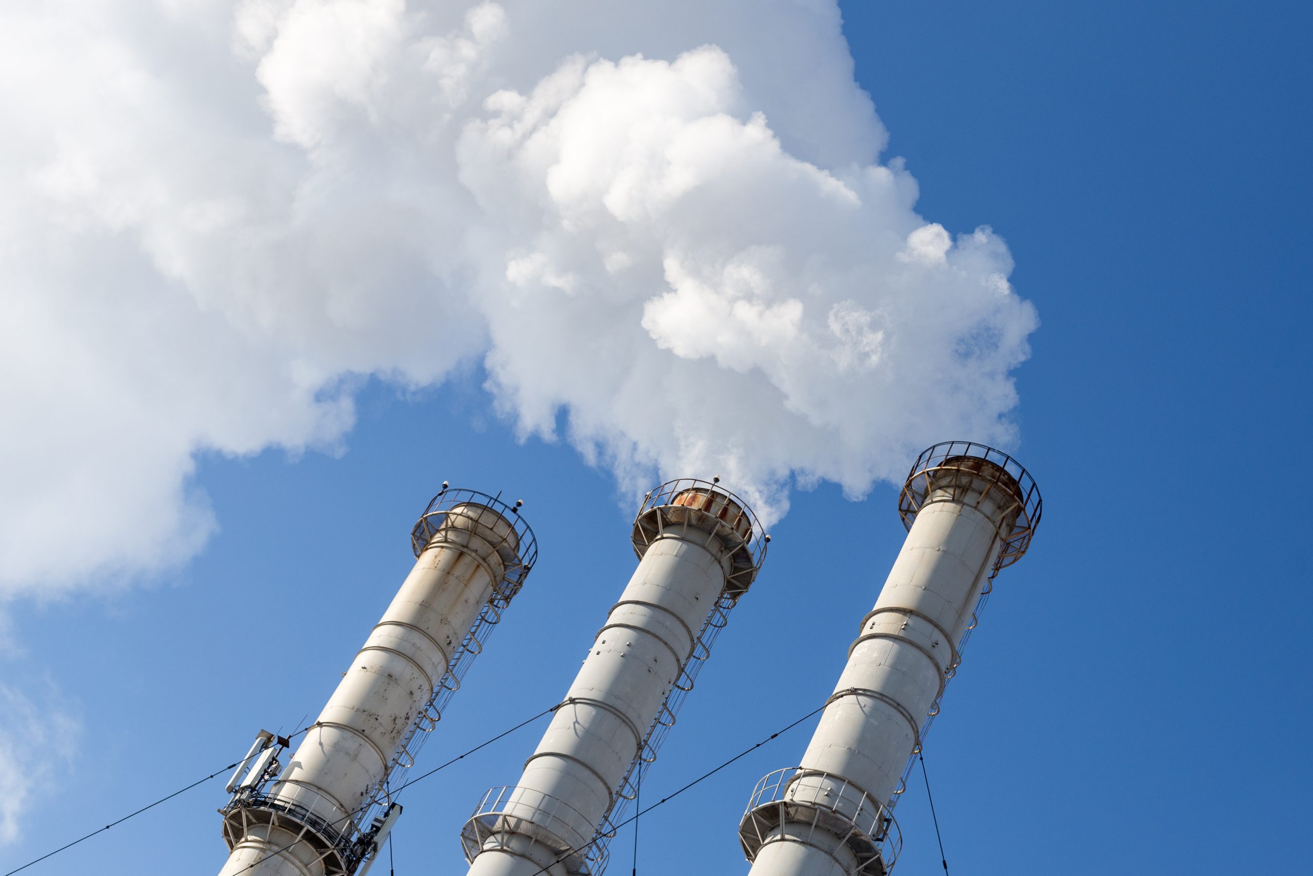 smoking pipes making clouds against blue sky background. dioxide air contamination. environmental pollution